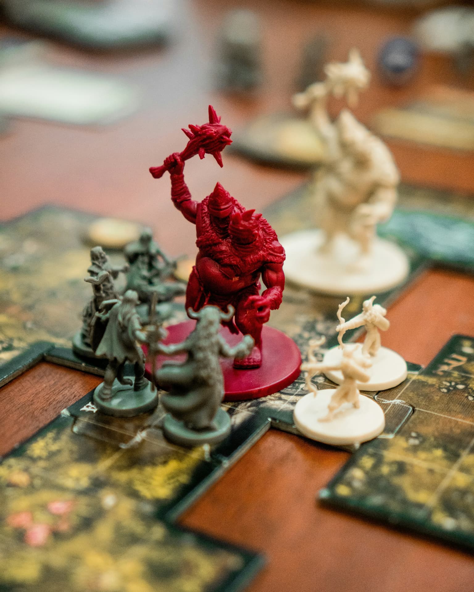 A party of adventurer miniatures facing a red ogre on a dungeon game board
